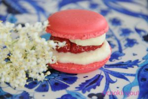 Un joli petit macaron tout rose parfumé à la fraise sur une ganache au sirop de fleurs de sureau.