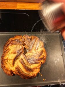 Saupoudrage de sucre glace sur le Kringle sortant du four